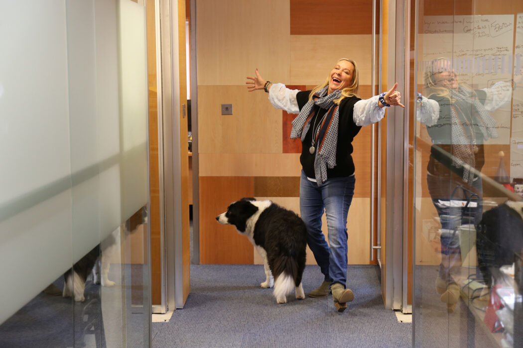 Jenny Kendall smiling with her arms in the air at the end of the hallway